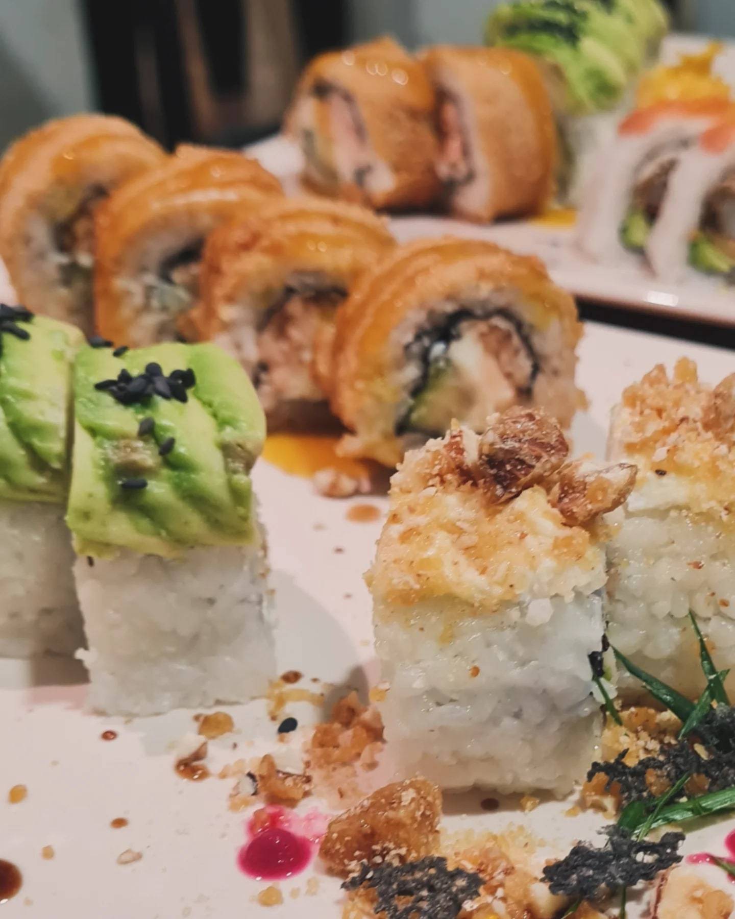 Rolls de sushi con palta y sésamo negro, salmón sopleteado y cobertura crocante