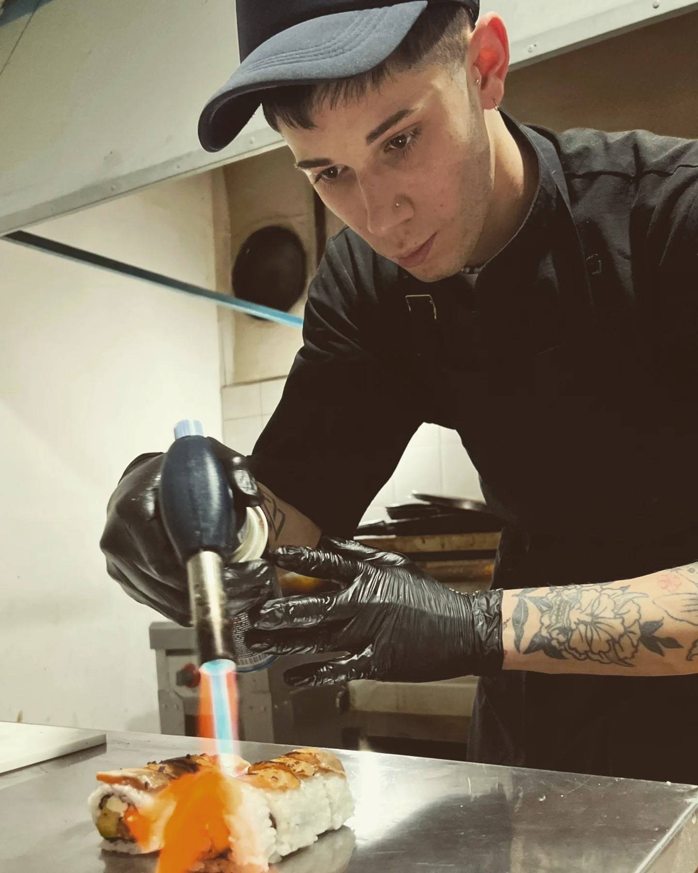Ariel Dante Llensa con guantes negros, concentrado mientras usa un soplete en la cocina